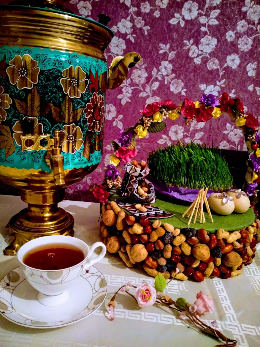 A decorated samovar, a cup of tea and a tray of sprouted wheat and sweets for Novruz