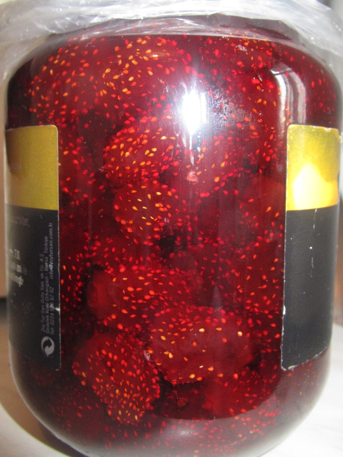 A glass jar of whole strawberries preserved in syrup