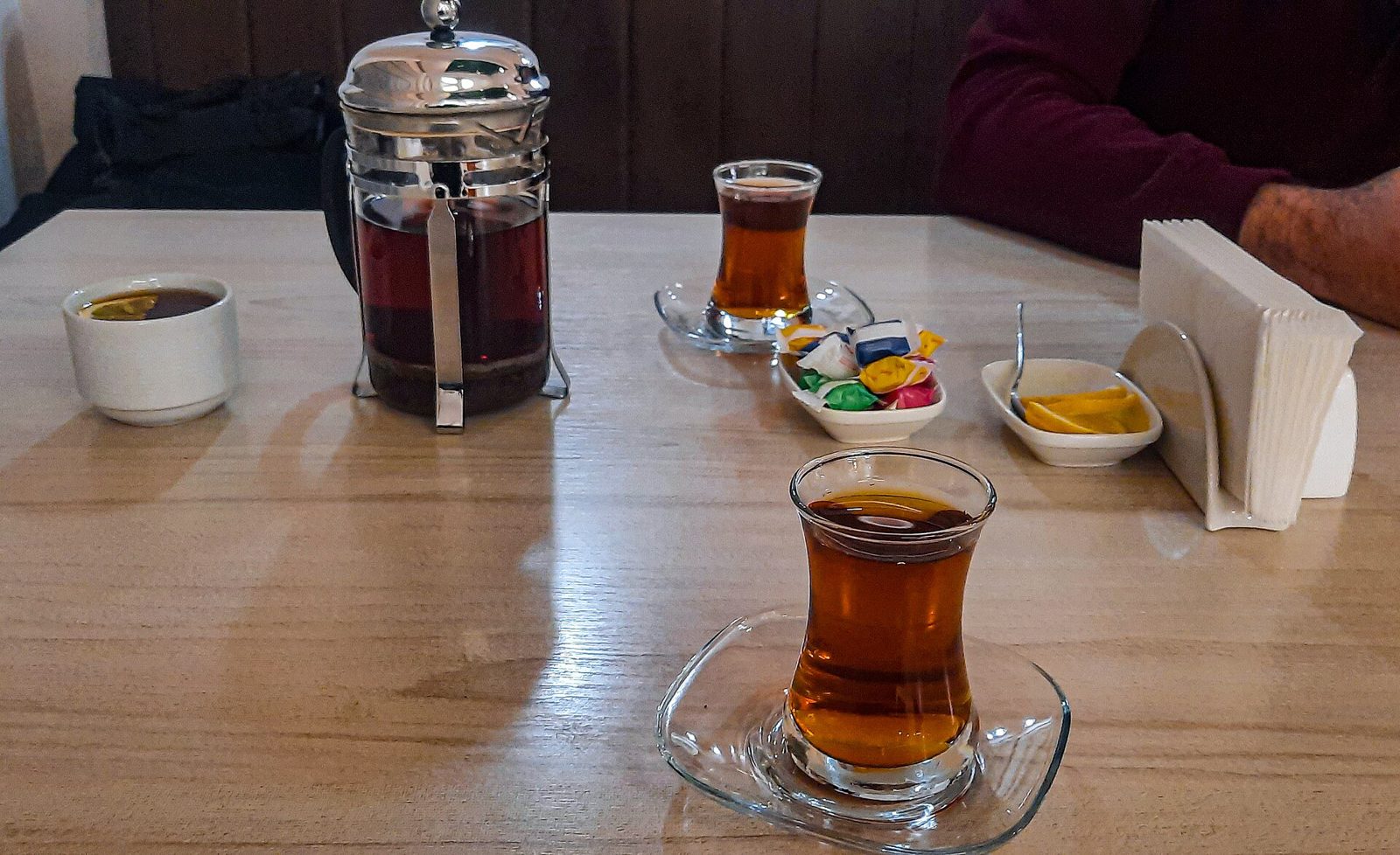 Two armudu glasses of tea on a café table in Baku, with a teapot, sweets and lemon