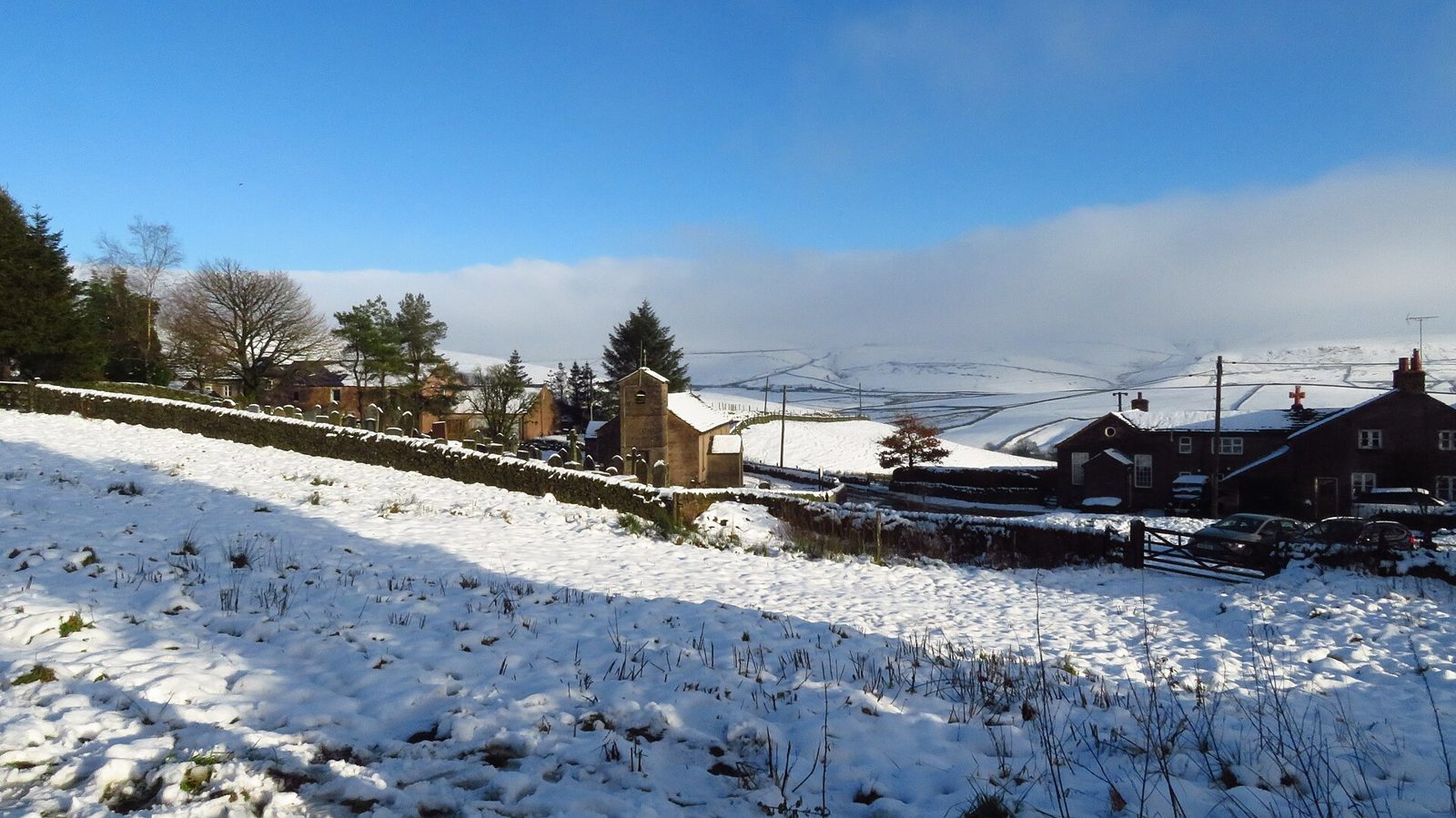 Snowy fields and houses in the Cheshire hills under a blue sky