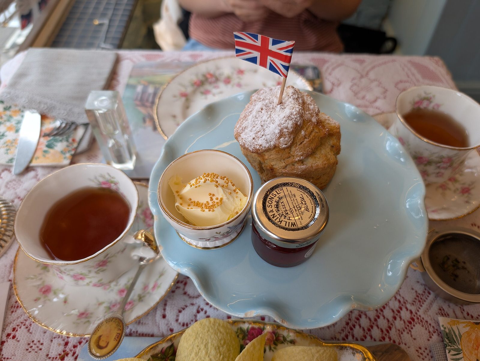 A cream tea with scones, clotted cream, jam and a cup of black tea, with a small Union flag