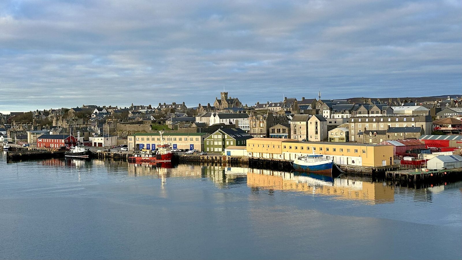 Lerwick harbour in Shetland with houses reflected in calm water