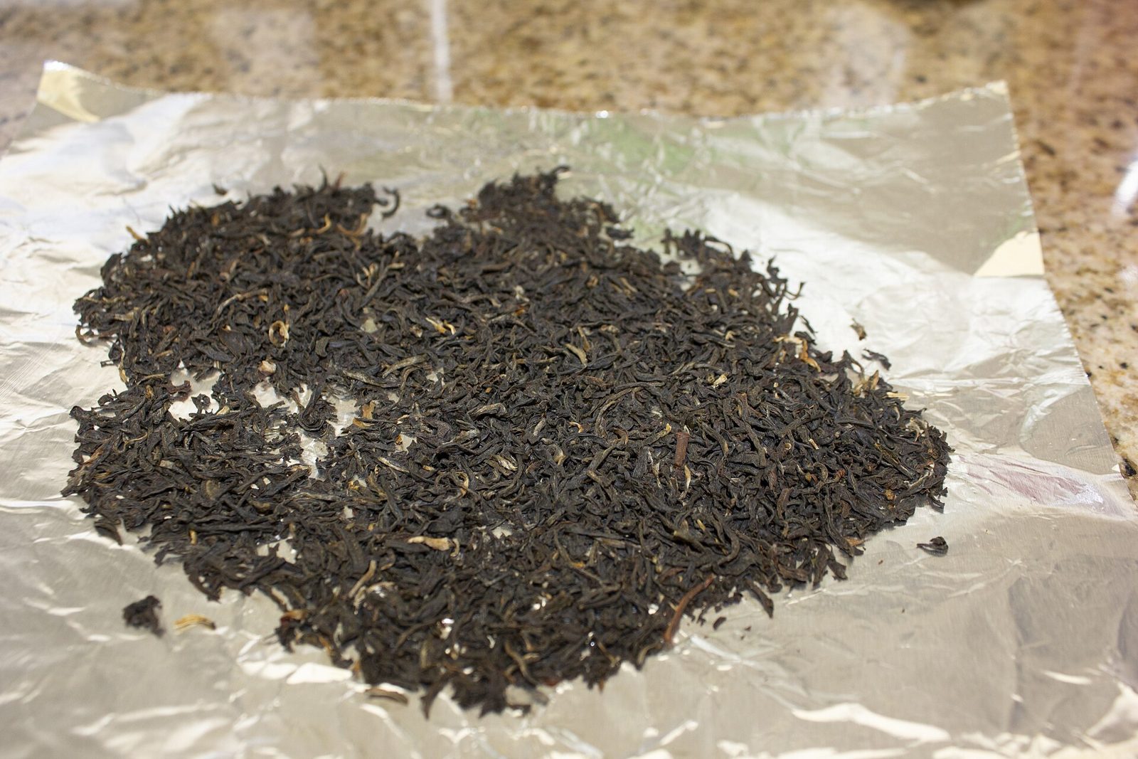 A pile of dry loose leaf black tea on foil